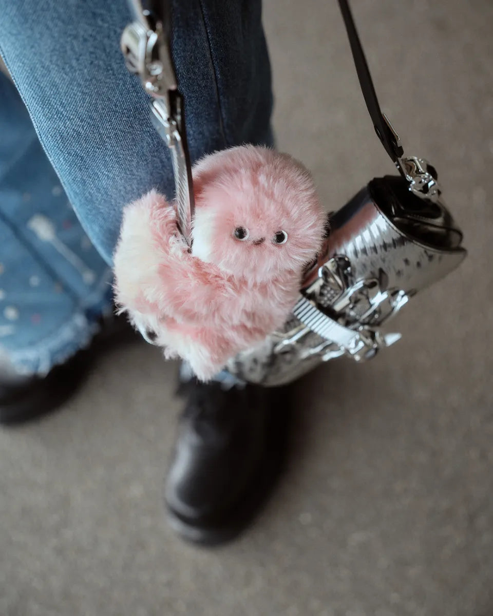 Pink interactive fluffy bag charm attached to a handbag